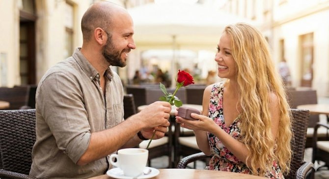 Romantick&eacute; gesto v kav&aacute;rně: Muž před&aacute;v&aacute; sv&eacute; př&iacute;telkyni růži a malou d&aacute;rkovou krabičku, ide&aacute;ln&iacute; pro &scaron;perk nebo parf&eacute;m z e-shopu Notino. Inspirace na valent&yacute;nsk&yacute; d&aacute;rek pro ženy, kter&yacute; potě&scaron;&iacute; a nezruinuje rozpočet.