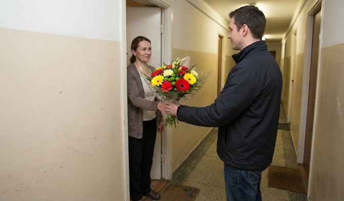 Kurýr předávající kytici zákaznici z e-shopu KvětinyExpres zakoupenou s využitím slevové akce